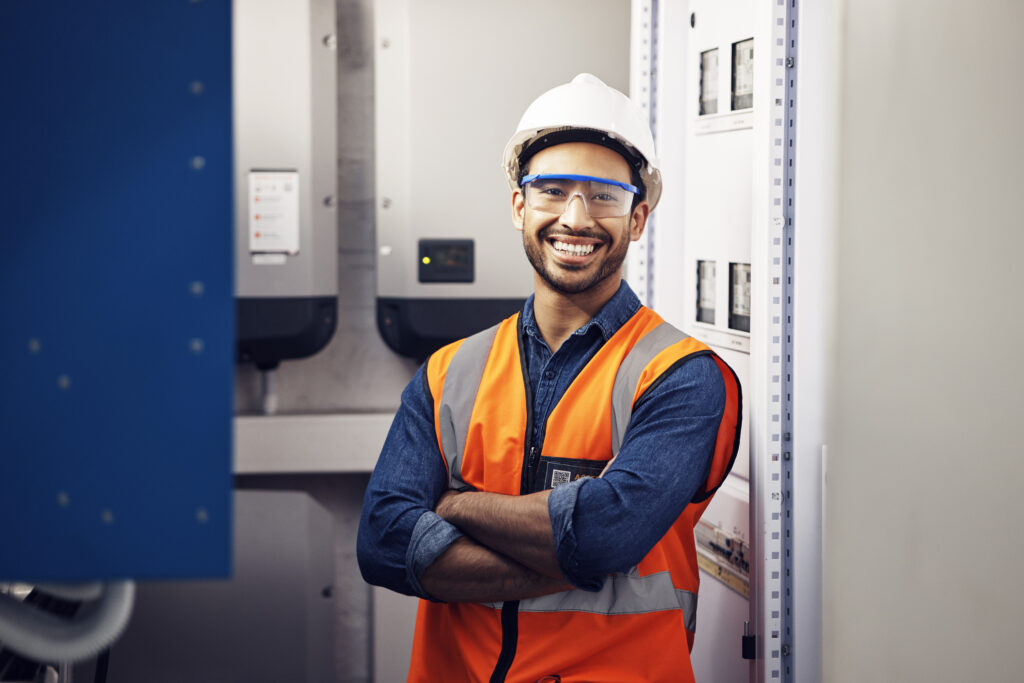 Portrait, happy man and engineering technician in control room, inspection service or industry maintenance. Electrician, arms crossed and smile in electrical substation, system or industrial mechanic.